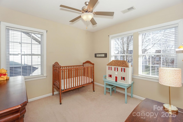 carpeted bedroom with a nursery area and ceiling fan