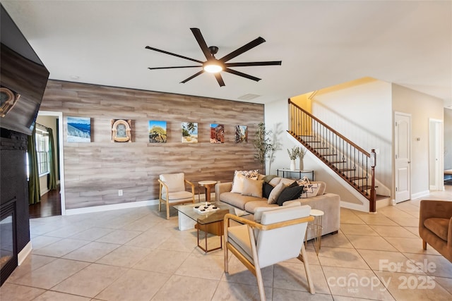 living room featuring wood walls, ceiling fan, and light tile patterned floors