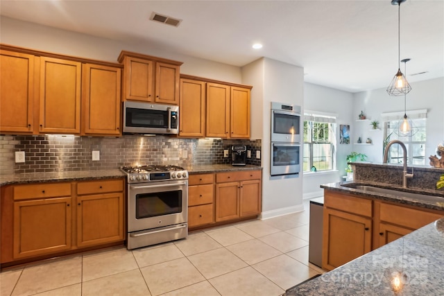 kitchen featuring pendant lighting, stainless steel appliances, backsplash, dark stone countertops, and sink