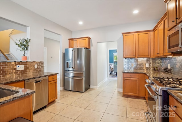 kitchen featuring appliances with stainless steel finishes, dark stone countertops, and light tile patterned floors