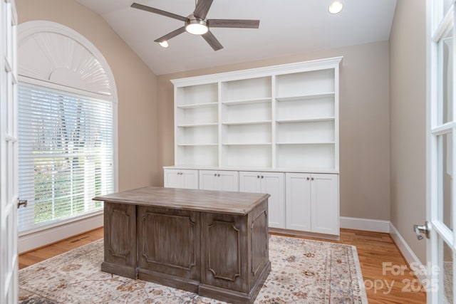 home office with ceiling fan, light hardwood / wood-style floors, and lofted ceiling