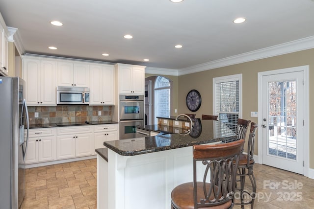 kitchen featuring white cabinets, a breakfast bar, stainless steel appliances, and sink