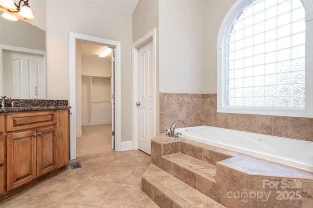 bathroom with vanity and tiled tub