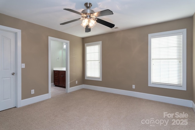 unfurnished bedroom featuring ensuite bath, ceiling fan, and light colored carpet