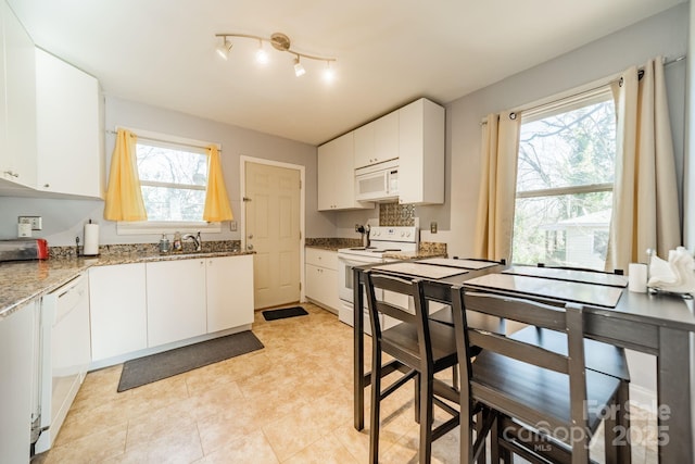 kitchen featuring white cabinetry, sink, white appliances, and light stone countertops