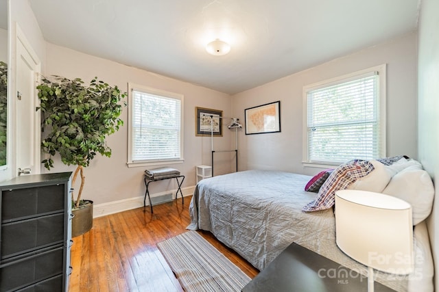 bedroom with multiple windows and hardwood / wood-style flooring