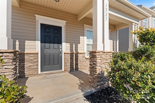 doorway to property featuring stone siding and a porch