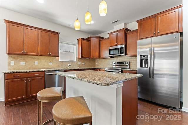 kitchen featuring hanging light fixtures, stainless steel appliances, a breakfast bar, and a kitchen island