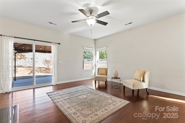 sitting room with dark wood-type flooring and ceiling fan