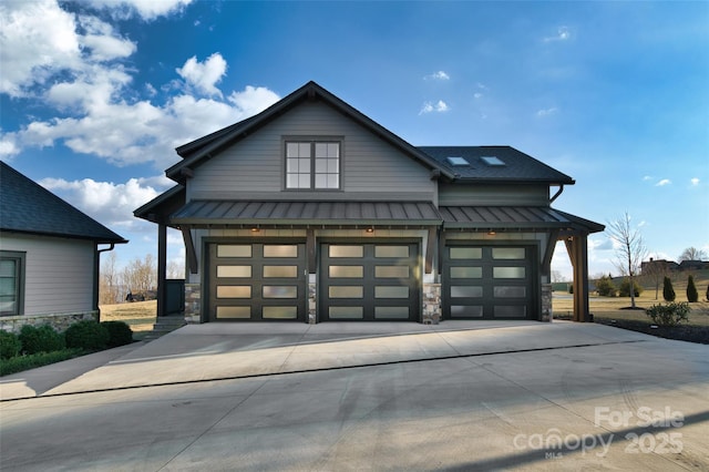 view of front of house featuring a standing seam roof, an attached garage, concrete driveway, stone siding, and metal roof