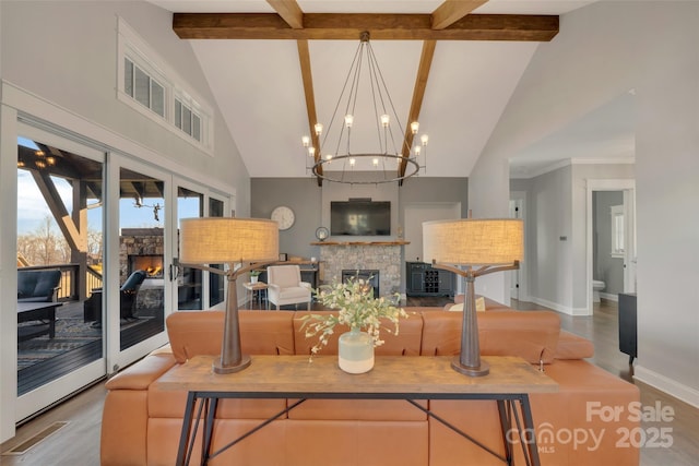 living area with baseboards, wood finished floors, beamed ceiling, and a glass covered fireplace