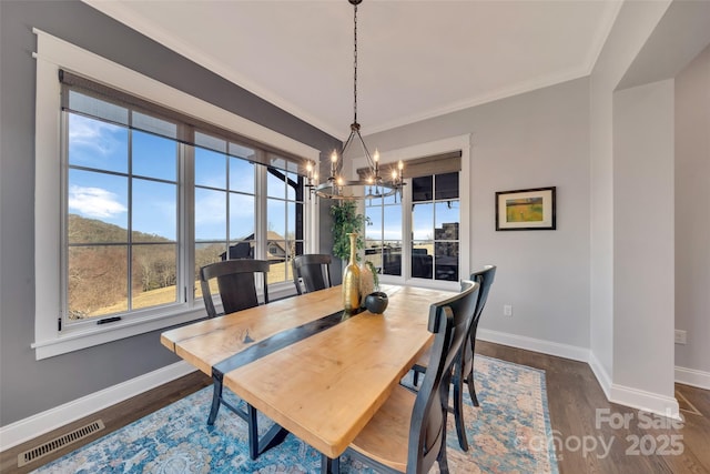 dining area featuring baseboards, visible vents, dark wood-style flooring, crown molding, and a notable chandelier