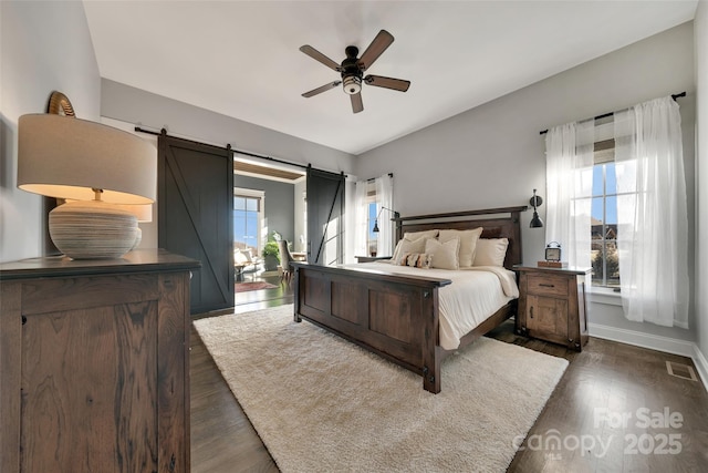 bedroom with visible vents, multiple windows, dark wood-style floors, and a barn door