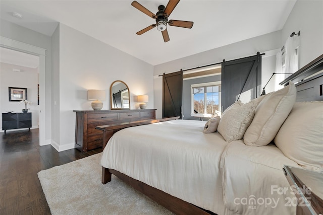 bedroom featuring a ceiling fan, a barn door, wood finished floors, and baseboards