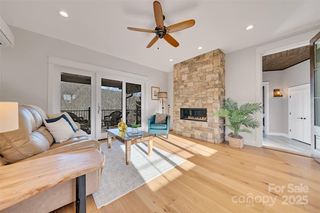 living area with a stone fireplace, recessed lighting, a ceiling fan, and light wood-style floors