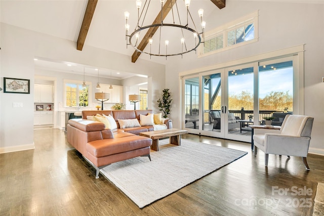 living room with beamed ceiling, an inviting chandelier, and wood finished floors