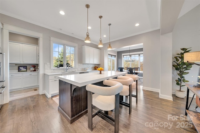 kitchen with a center island, white cabinets, light countertops, decorative backsplash, and a healthy amount of sunlight