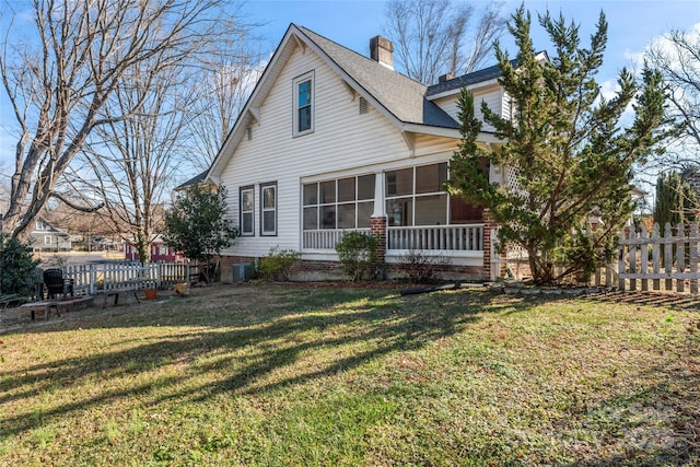 rear view of property featuring a lawn and a sunroom