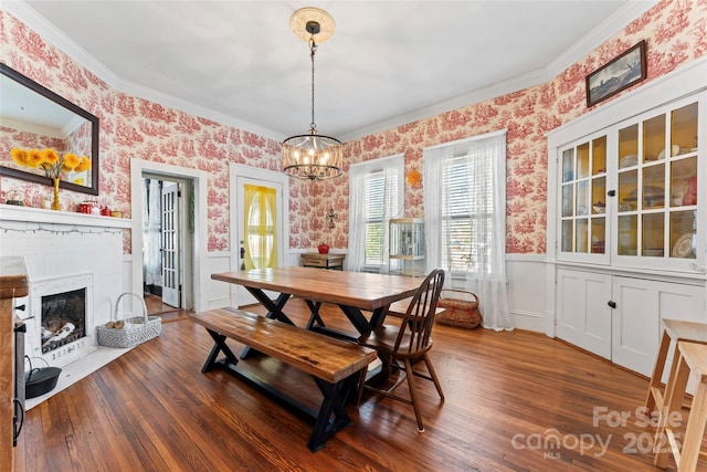 dining room with a fireplace, an inviting chandelier, crown molding, and dark hardwood / wood-style floors