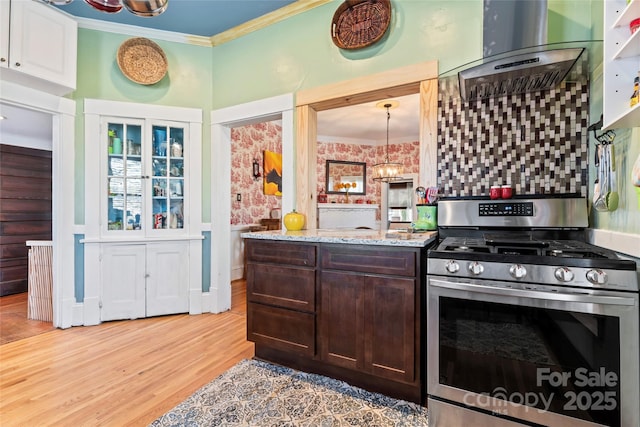 kitchen featuring light hardwood / wood-style flooring, pendant lighting, gas stove, ornamental molding, and dark brown cabinetry