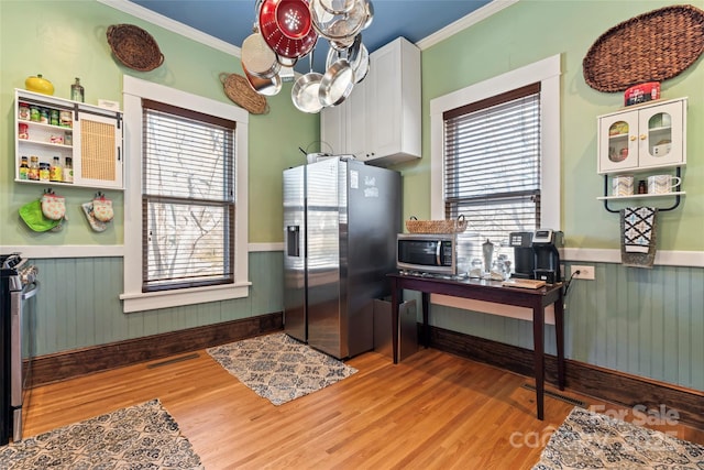 kitchen featuring a chandelier, light wood-type flooring, crown molding, white cabinets, and appliances with stainless steel finishes