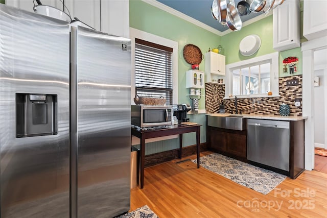 kitchen with sink, white cabinets, light wood-type flooring, and appliances with stainless steel finishes