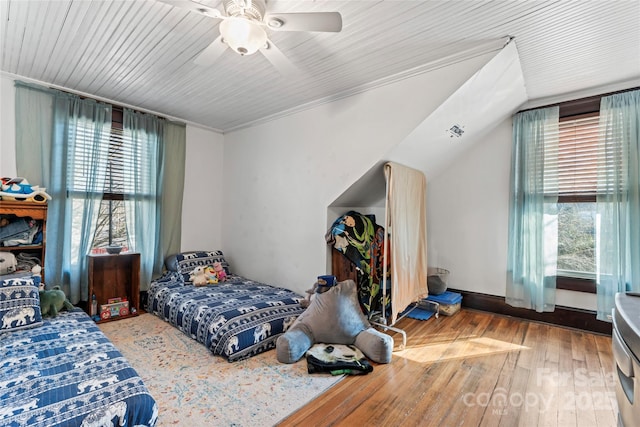 bedroom with ceiling fan, ornamental molding, multiple windows, and wood-type flooring