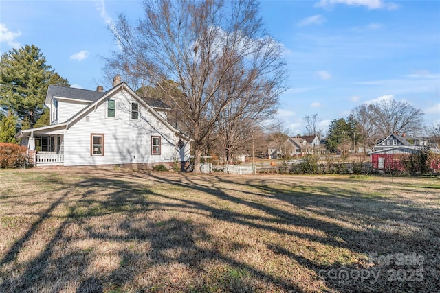 view of side of home with a porch and a lawn