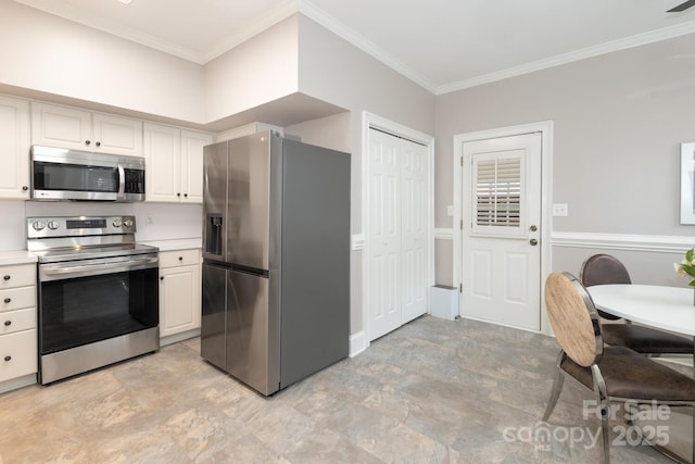 kitchen with white cabinets, ornamental molding, and stainless steel appliances