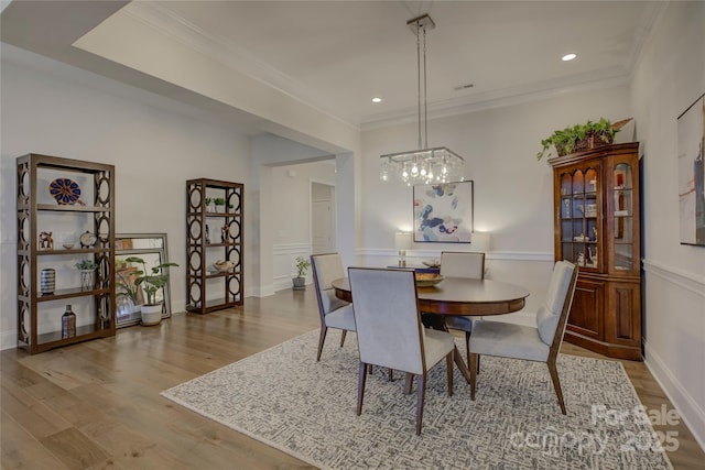 dining area with ornamental molding and light hardwood / wood-style floors