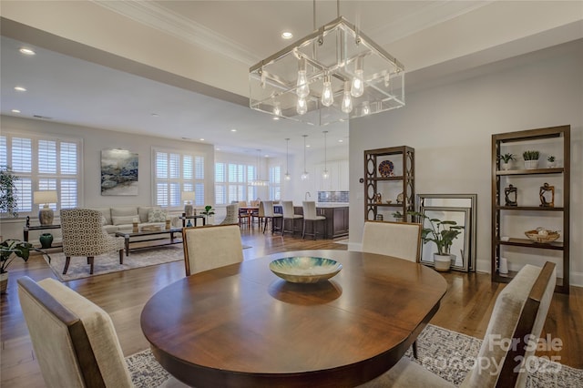 dining room featuring an inviting chandelier, crown molding, dark hardwood / wood-style floors, and a healthy amount of sunlight