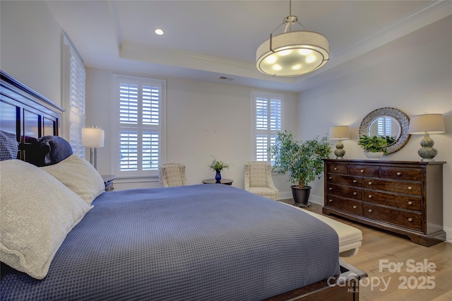 bedroom featuring crown molding, wood-type flooring, and a raised ceiling