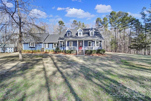 cape cod-style house with a front yard, covered porch, and a storage shed