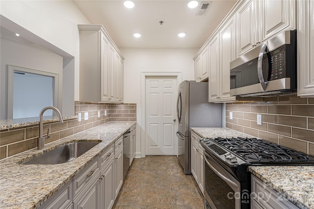 kitchen featuring sink, stainless steel appliances, tasteful backsplash, light stone counters, and white cabinets