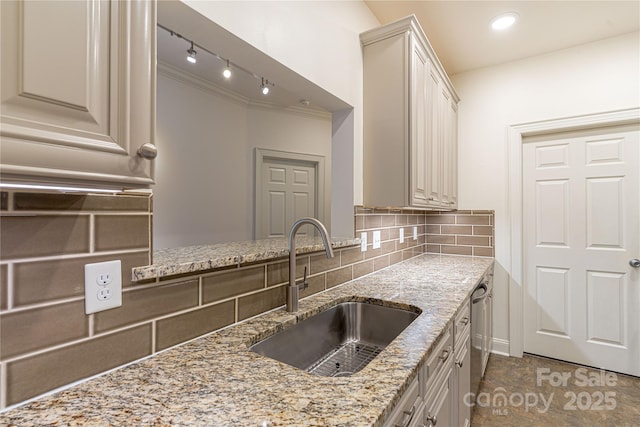 kitchen featuring rail lighting, sink, stainless steel dishwasher, decorative backsplash, and light stone counters