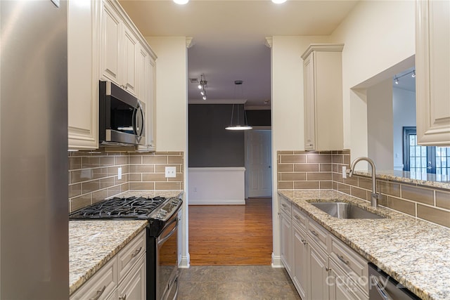 kitchen with backsplash, light stone countertops, sink, and stainless steel appliances