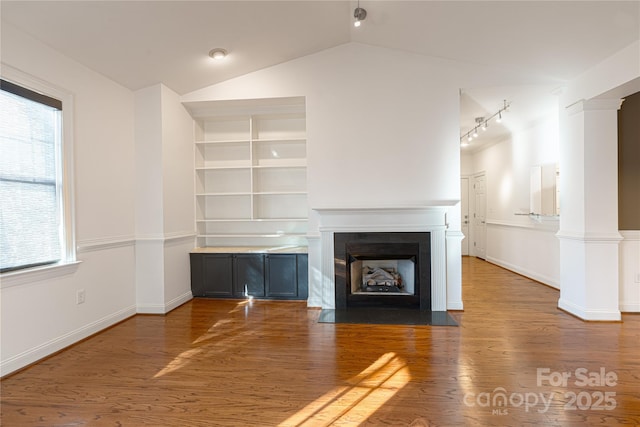 unfurnished living room featuring hardwood / wood-style flooring, built in shelves, and lofted ceiling