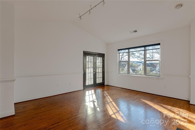 unfurnished room with hardwood / wood-style flooring, track lighting, lofted ceiling, and french doors