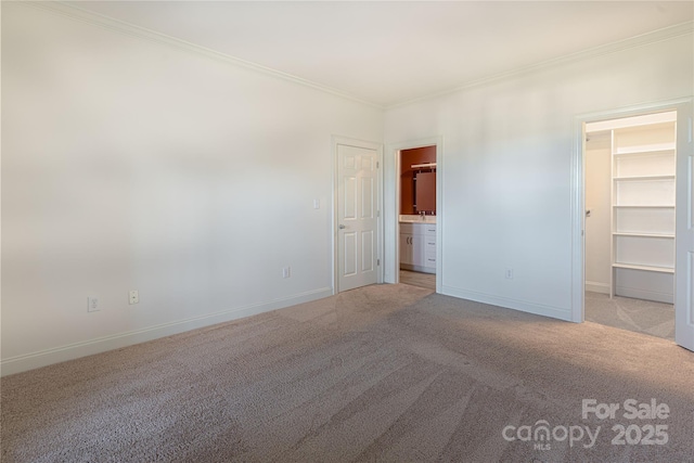 unfurnished bedroom featuring a walk in closet, crown molding, and light carpet