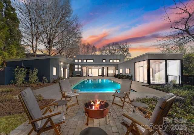 pool at dusk featuring a patio area and an outdoor fire pit