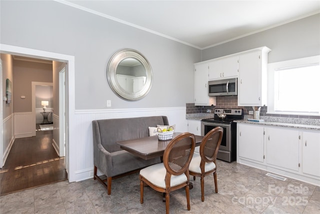 dining space with breakfast area, light tile patterned flooring, and ornamental molding