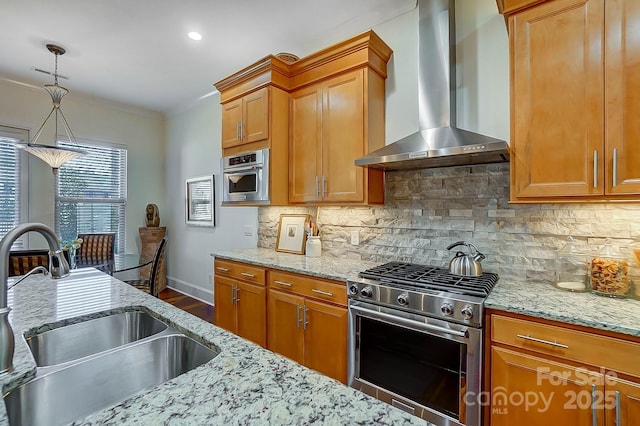 kitchen featuring wall chimney exhaust hood, sink, pendant lighting, stainless steel appliances, and decorative backsplash