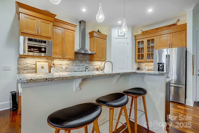 kitchen featuring dark wood-type flooring, tasteful backsplash, decorative light fixtures, appliances with stainless steel finishes, and wall chimney range hood