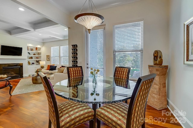 dining room with wood-type flooring, a wealth of natural light, built in features, and beamed ceiling