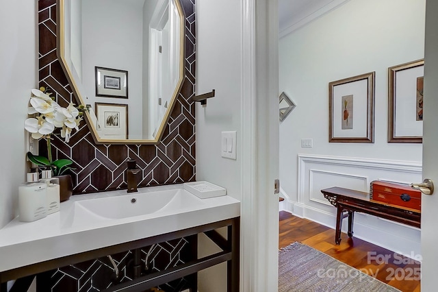 bathroom with crown molding, hardwood / wood-style floors, and vanity