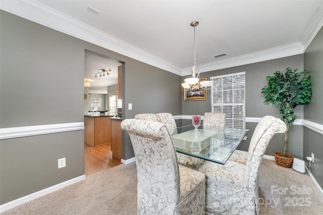 dining room featuring light carpet, crown molding, and an inviting chandelier