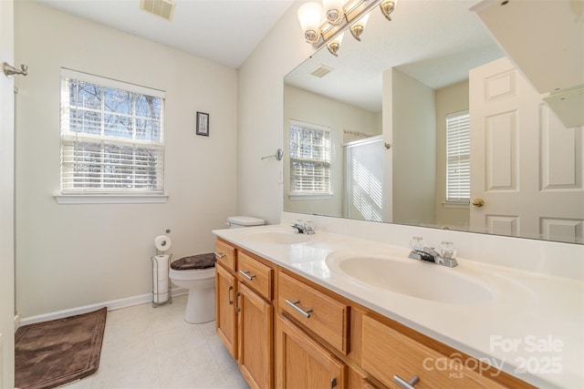 bathroom featuring tile patterned flooring, vanity, a shower with shower door, and toilet