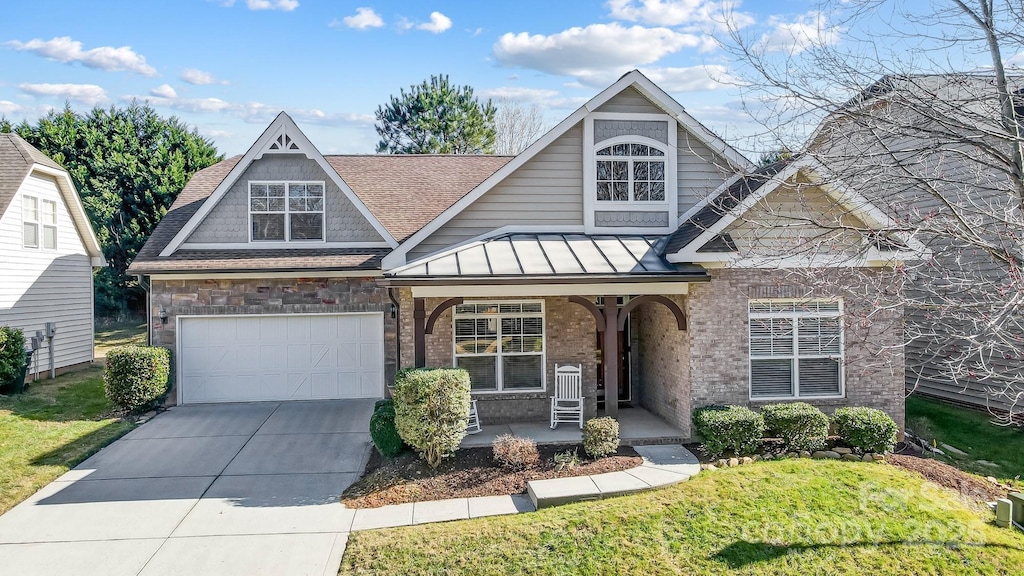 view of front of house featuring covered porch, a front yard, and a garage