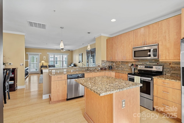 kitchen featuring appliances with stainless steel finishes, ceiling fan, a center island, and kitchen peninsula