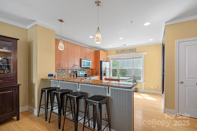 kitchen with kitchen peninsula, tasteful backsplash, a kitchen bar, dark stone counters, and appliances with stainless steel finishes